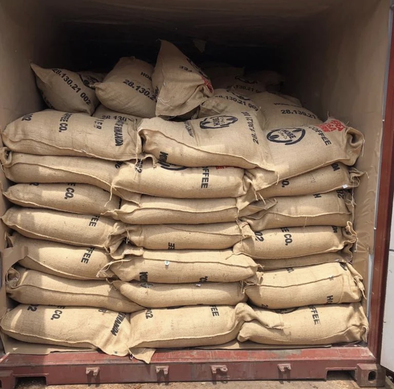 Stacked burlap sacks branded Hobe Coffee Co. loaded inside a shipping container